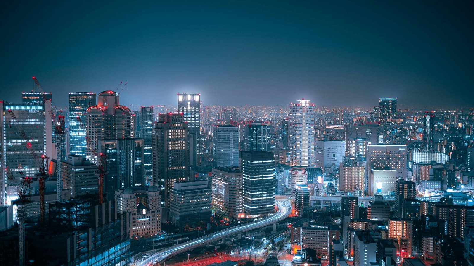 Vista panorâmica de cidade grande com prédios iluminados e avenidas urbanas