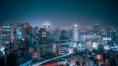 Vista panorâmica de cidade grande com prédios iluminados e avenidas urbanas