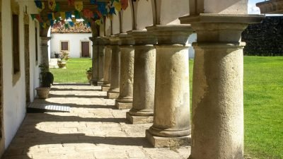 Interior externo de construção religiosa com colunas, jardim e arquitetura antiga